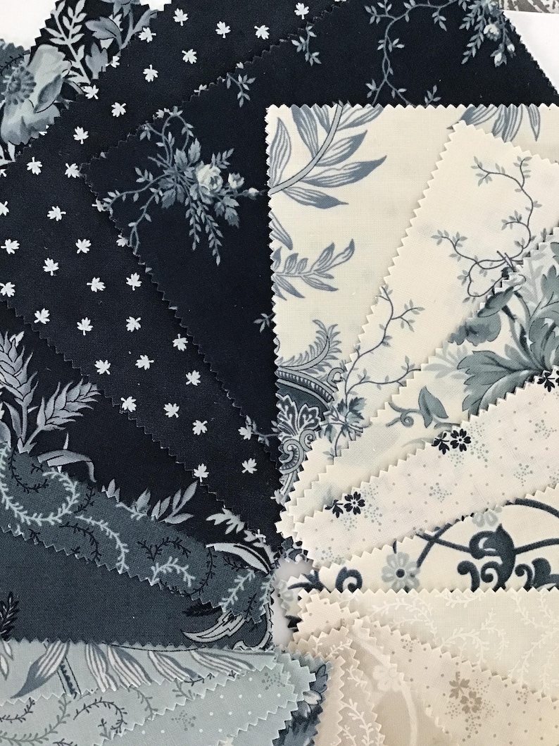 Peut inclure: Une collection d'&eacute;chantillons de tissu dispos&eacute;s en &eacute;ventail, pr&eacute;sentant divers motifs dans des tons bleu marine, gris ardoise et cr&egrave;me. Les designs incluent des motifs floraux, de petites feuilles et des illustrations botaniques aux bords dentel&eacute;s.
