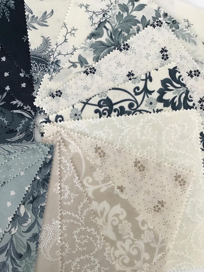 Peut inclure: Un ensemble d'&eacute;chantillons de tissu carr&eacute;s dispos&eacute;s en &eacute;ventail, pr&eacute;sentant divers motifs dans des tons bleu marine, gris ardoise, cr&egrave;me et beige. Les pi&egrave;ces de tissu ont des bords dentel&eacute;s et affichent des motifs floraux et damass&eacute;s.