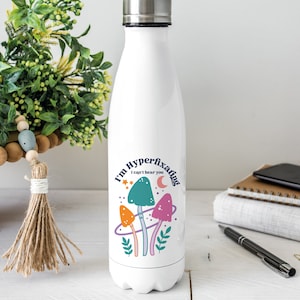 May include: White stainless steel water bottle with a colourful mushroom graphic and the text "I'm Hyperfixating I can't hear you".