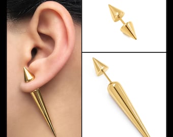 Puede incluir: Un par de pendientes de espiga de tono dorado. Los pendientes están hechos de metal y tienen un diseño puntiagudo y afilado. Los pendientes se muestran en la oreja de una modelo.