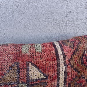 May include: Close-up of a red, brown, and cream patterned rug with a geometric design. The rug is made of woven fabric and has a soft, textured surface.