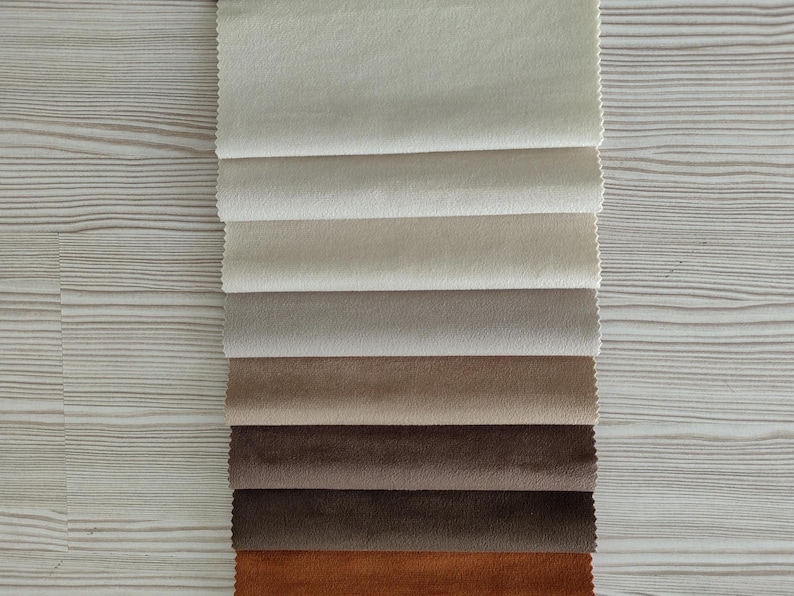 May include: A vertical stack of seven rectangular fabric swatches arranged in a gradient from light cream to dark brown. Each swatch features a soft, matte texture with clean, pinked edges, showcasing a neutral color palette of beige, tan, and brown.