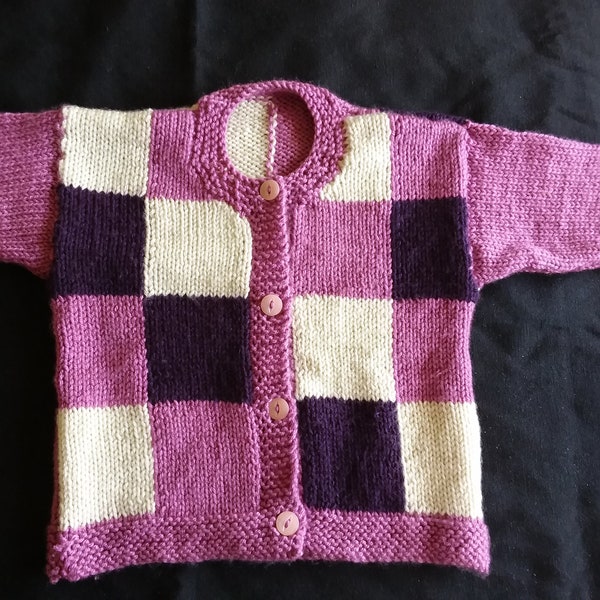 Child's hand knitted cardigan with pink, purple and white squares to body and plain pink sleeves. Approx 4-5 years.