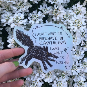 May include: A white sticker with a black and white illustration of a wolf with the text "I don't want to participate in capitalism I just want to scream!"
