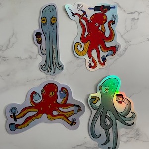 Può includere: Quattro adesivi olografici con polpi dei cartoni animati. Un polpo blu tiene in mano una tazza di caffè. Un polpo rosso sta cuocendo con un mattarello e una frusta. Un altro polpo rosso tiene in mano delle tazze di caffè. Un polpo verde tiene in mano una tazza di caffè.