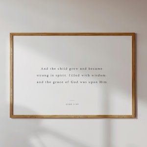 Könnte beinhalten: Ein gerahmter Druck mit weißem Hintergrund und schwarzem Text. Der Text lautet "Und das Kind wuchs und wurde stark im Geist, erfüllt von Weisheit: und die Gnade Gottes war auf ihm." Der Text "LUKAS 2:40" ist zentriert unter dem Zitat.