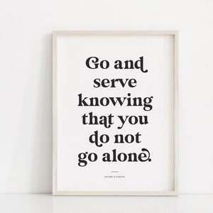 May include: A black and white inspirational quote print in a light wood frame. The quote reads "Go and serve knowing that you do not go alone."  The quote is attributed to Henry B. Eyring.