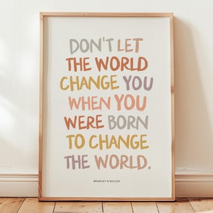 May include: A framed print featuring a motivational quote in colourful text: "Don't let the world change you when you were born to change the world." The quote is attributed to Bradley R Wilcox.