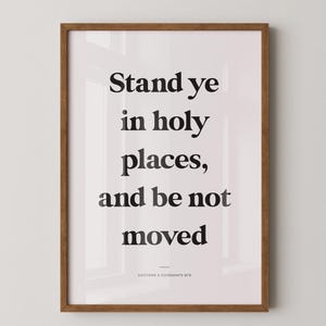 Può includere: Stampa incorniciata con il testo "Stand ye in holy places, and be not moved" in nero. La cornice è marrone caldo e lo sfondo è bianco tenue. Il testo "Doctrine & Covenants 87:8" è in basso.