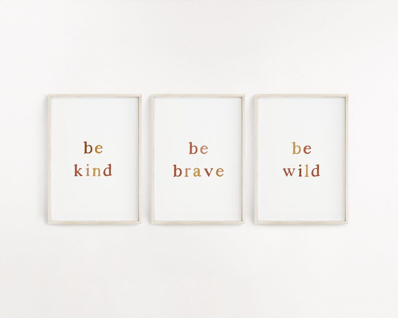 May include: Three framed prints with the words "be kind", "be brave", and "be wild" in a gradient of brown, orange, and yellow.