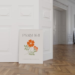 K&ouml;nnte beinhalten: Ein gerahmter Druck mit dem Text "PSALM 16:11" und einer floralen Illustration mit orangefarbenen und rosa Bl&uuml;ten und gr&uuml;nen Bl&auml;ttern. Der Druck enth&auml;lt auch den Text "IN HIS PRESENCE THERE IS FULLNESS OF JOY". Der Druck lehnt an einer wei&szlig;en T&uuml;r.