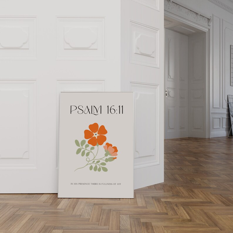 K&ouml;nnte beinhalten: Ein gerahmter Druck mit dem Text "PSALM 16:11" und einer floralen Illustration mit orangefarbenen und rosa Bl&uuml;ten und gr&uuml;nen Bl&auml;ttern. Der Druck enth&auml;lt auch den Text "IN HIS PRESENCE THERE IS FULLNESS OF JOY". Der Druck lehnt an einer wei&szlig;en T&uuml;r.