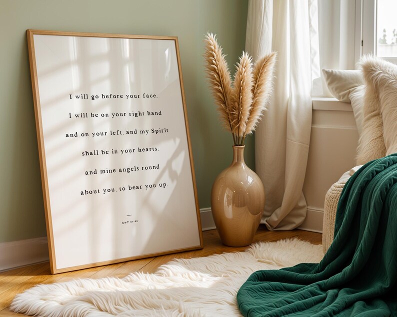 K&ouml;nnte beinhalten: Ein gerahmter Druck mit hellem Holzrahmen zeigt inspirierenden Text in schwarzer Schrift. Eine beige Vase enth&auml;lt getrocknetes Pampasgras. Eine gr&uuml;ne Decke und ein wei&szlig;er Kunstfellteppich verleihen dem Raum Textur. Der Text lautet: "I will go before your face..."