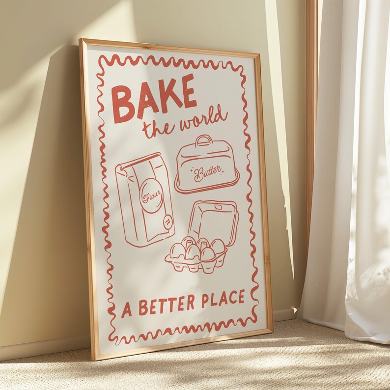 May include: A framed print with a red border and white background. The print features a red illustration of baking supplies with the text "BAKE the world a better place".