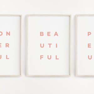 May include: Three framed prints with the words "Wonderful", "Beautiful", and "Powerful" written in pink letters on a white background.