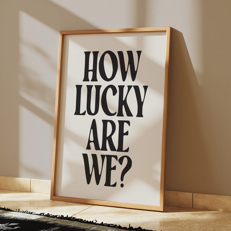 May include: A framed print with the text "HOW LUCKY ARE WE?" in bold, black letters on a white background.