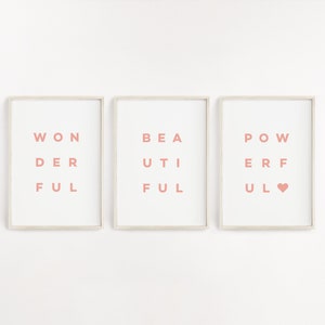 May include: Three framed prints with the words "WONDERFUL", "BEAUTIFUL", and "POWERFUL" spelled out in a unique way. The words are in a light pink color and the frames are white.