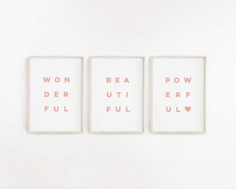 May include: Three framed prints with the words "WONDERFUL", "BEAUTIFUL", and "POWERFUL" spelled out in a unique way. The words are in a light pink color and the frames are white.