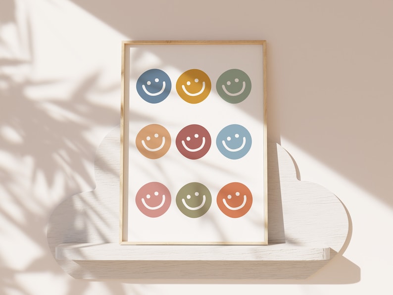May include: A framed print with nine colorful smiley faces in a grid pattern. The background is white and the frame is light wood.