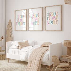 May include: Three framed prints with the text "Jesus is my" followed by "Friend", "Hope", and "Light". The prints are in a white room with a white bed and a wooden rocking horse.