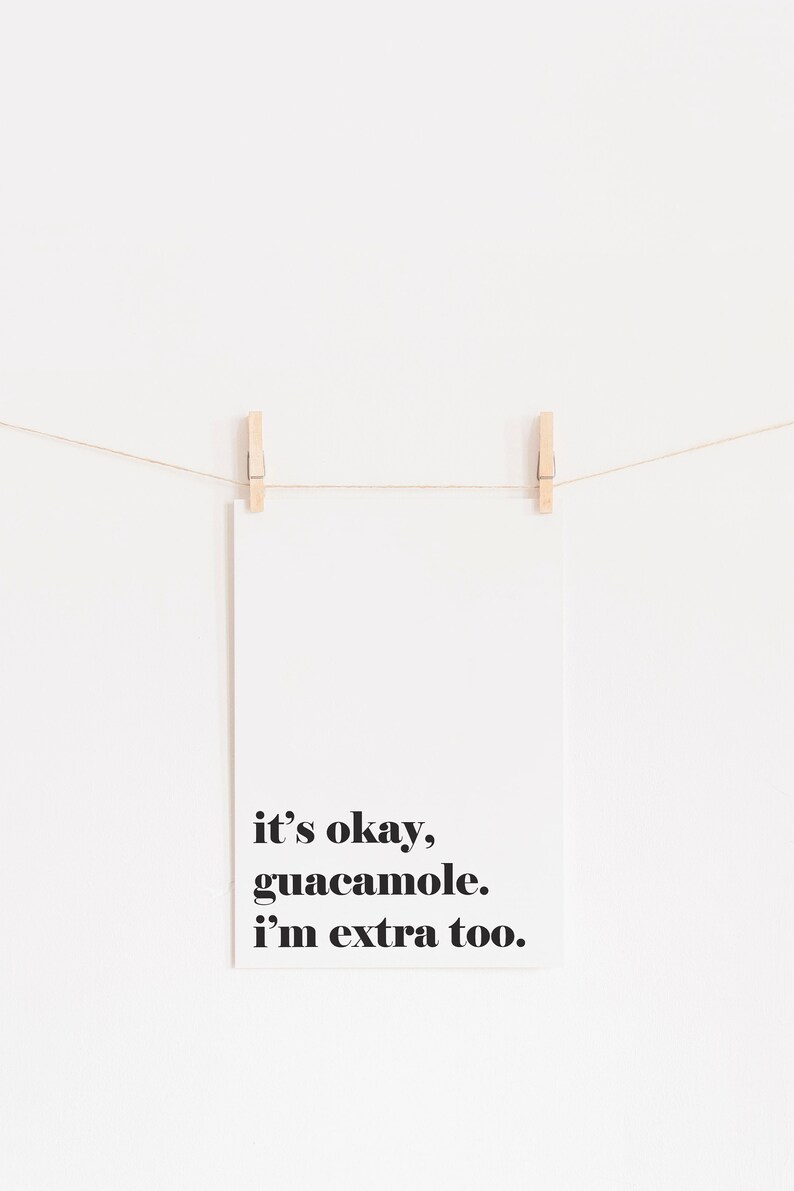 Puede incluir: Una tarjeta blanca con texto negro que dice "it's okay, guacamole. i'm extra too." La tarjeta est&aacute; colgada de una cuerda con dos pinzas de madera.