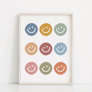 May include: A framed print with nine colorful smiley faces in various shades of blue, green, yellow, orange, and red. The smiley faces are arranged in three rows of three.