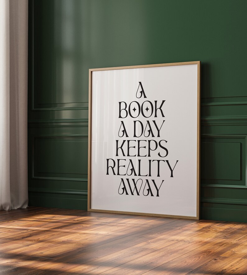 May include: A framed print with a white background and black text that reads "A book a day keeps reality away". The frame is a light wood color and the print is hanging on a dark green wall.