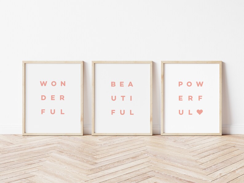 May include: Three framed prints with the words "Wonderful", "Beautiful", and "Powerful" spelled out in a unique way with the letters arranged in a grid pattern. The words are printed in a light pink color on a white background.