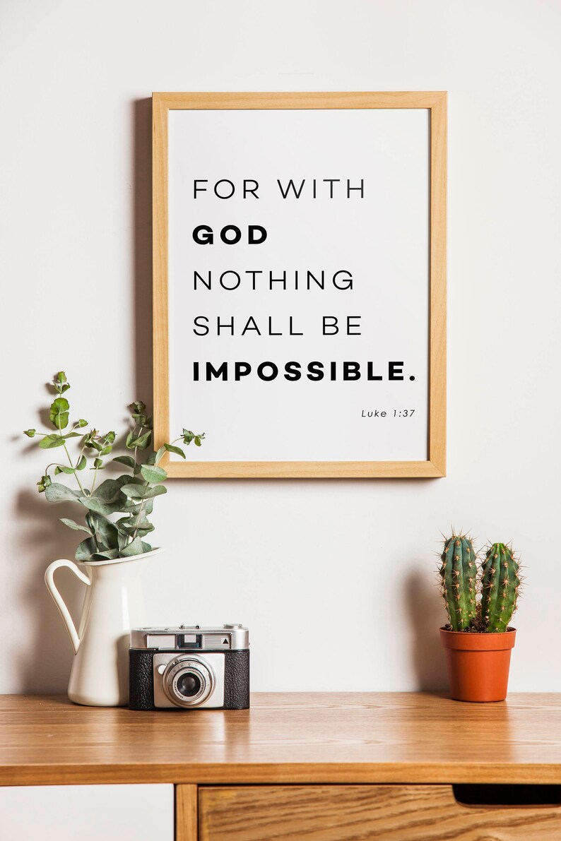 Puede incluir: Una impresi&oacute;n enmarcada con fondo blanco y texto negro que dice "Porque para Dios nada es imposible. Lucas 1:37". La impresi&oacute;n est&aacute; colgada en una pared blanca sobre una mesa de madera con una jarra blanca, una c&aacute;mara vintage y un cactus en maceta.