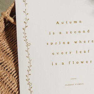 May include: A cream-colored card with gold text that reads "Autumn is a second spring where every leaf is a flower" by Albert Camus. A gold floral design runs along the left edge.