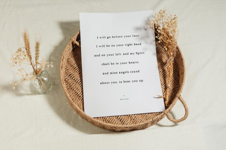 K&ouml;nnte beinhalten: Ein wei&szlig;er Druck mit inspirierendem Text liegt in einem runden Weidenkorb. Der Druck zeigt ein Zitat in schwarzem Text. Getrocknete Blumen und eine kleine Glasvase mit Weizen&auml;hren befinden sich auf der linken Seite des Korbs.