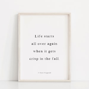 May include: A framed print with a white background and black text that reads "Life starts all over again when it gets crisp in the fall." The quote is attributed to F. Scott Fitzgerald.