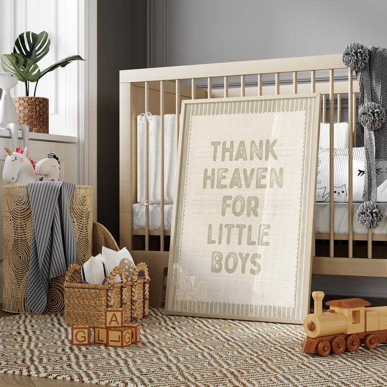 Puede incluir: Una escena de guarder&iacute;a con una cuna de madera, un cuadro enmarcado con la frase "Thank Heaven For Little Boys" y un tren de juguete de madera. Tambi&eacute;n se ven una cesta tejida y una alfombra con un dise&ntilde;o geom&eacute;trico. Peluches y una planta en maceta completan la decoraci&oacute;n.