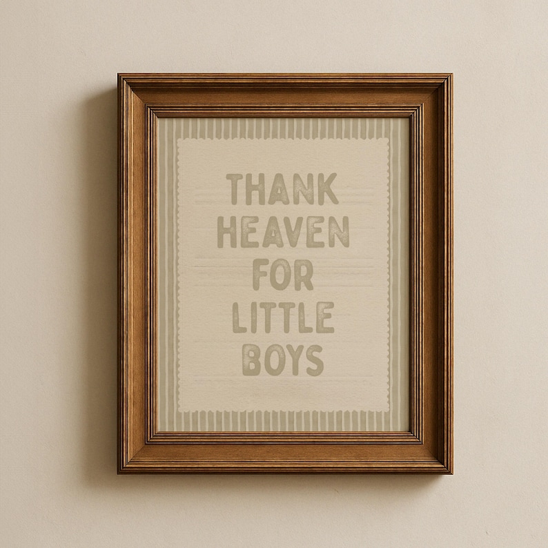 May include: A framed print with the text "THANK HEAVEN FOR LITTLE BOYS" in gray letters. The print has a light beige background with a striped border and is encased in a brown wooden frame.