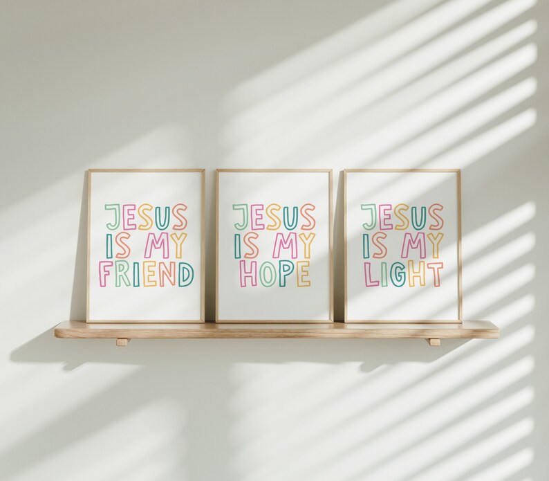 May include: Three framed prints with the text "Jesus is my" in colorful letters. The prints are hung on a wooden shelf. The first print says "Friend", the second says "Hope", and the third says "Light".