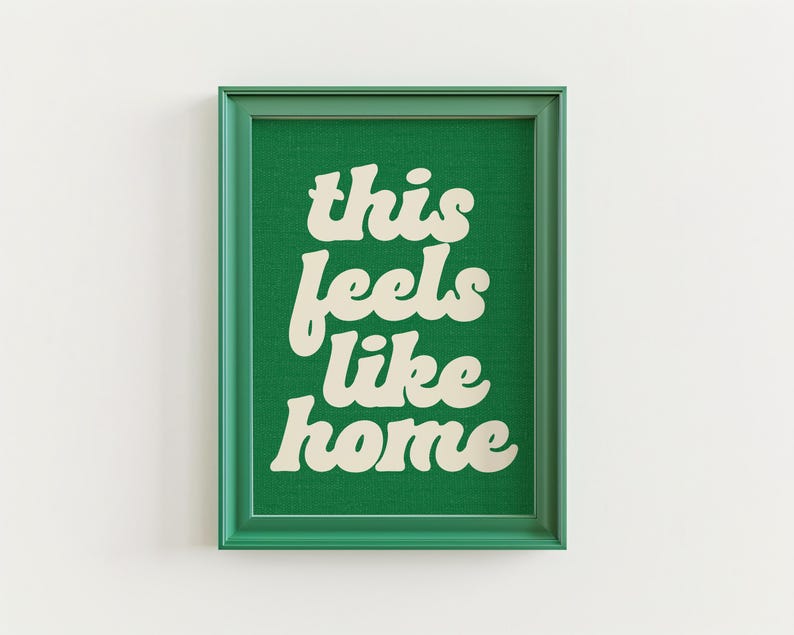 May include: A framed art print with the text "this feels like home" in a retro font. The text is cream-colored against a green background. The frame is green.