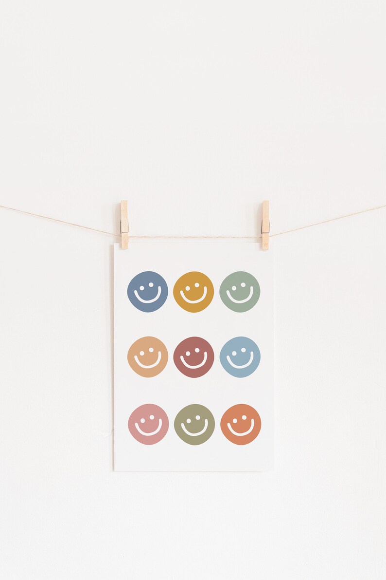 May include: A white card with nine colorful smiley faces printed on it. The card is hanging on a string with wooden clothespins.