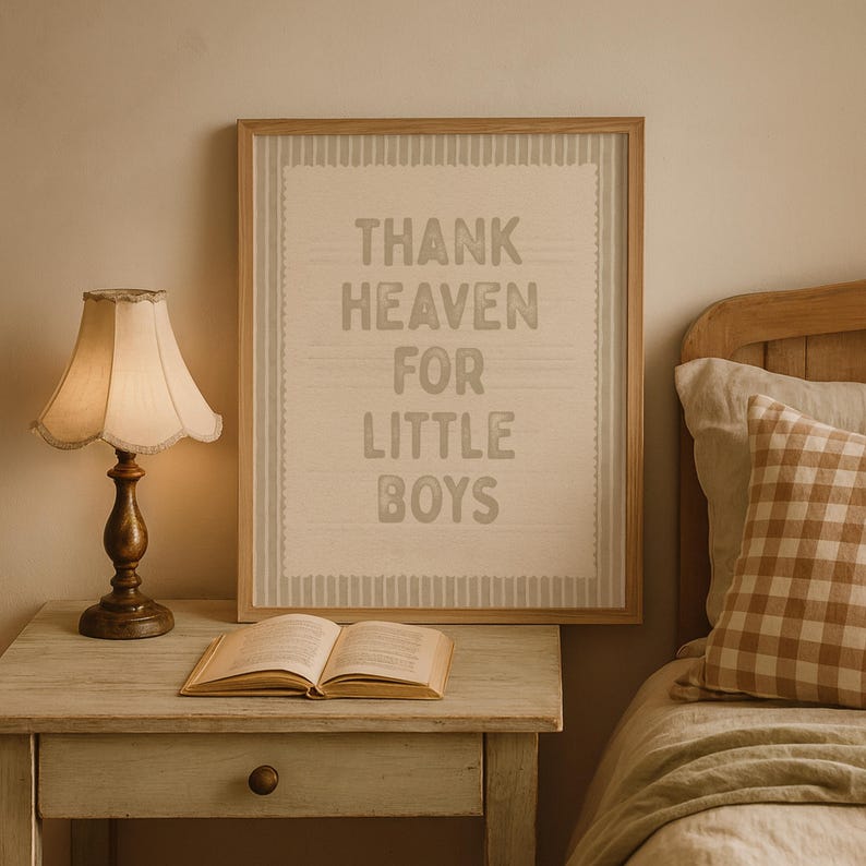 Puede incluir: Un cuadro enmarcado con el texto "THANK HEAVEN FOR LITTLE BOYS" cuelga sobre una mesita de noche. Una l&aacute;mpara con una pantalla beige y un libro est&aacute;n sobre la mesita. Una cama con una almohada a cuadros est&aacute; en el fondo.
