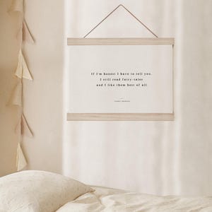May include: A framed print with the quote "If I'm honest I have to tell you. I still read fairy-tales and I like them best of all." The print is displayed on a light-colored wall above a bed with a patterned comforter.