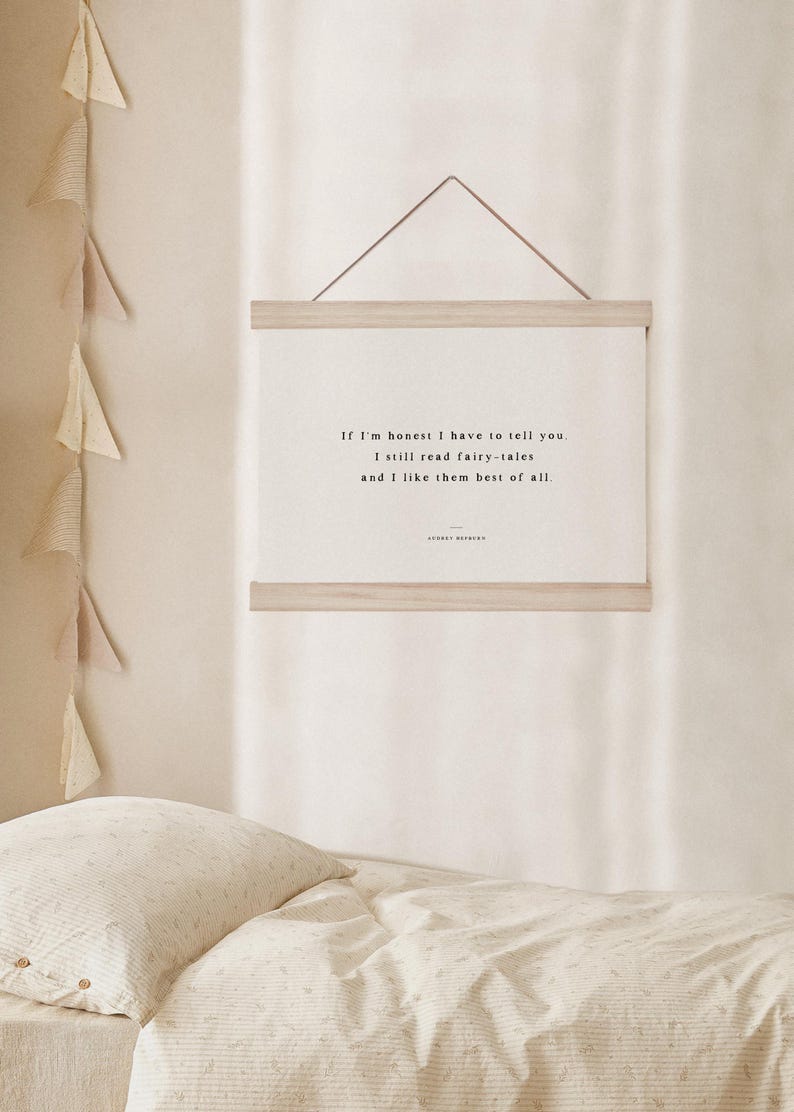 May include: A framed print with the quote "If I'm honest I have to tell you. I still read fairy-tales and I like them best of all." The print is displayed on a light-colored wall above a bed with a patterned comforter.