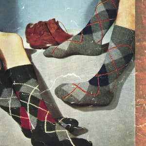Puede incluir: Un par de calcetines grises de punto de rombos con detalles rojos y amarillos. Los calcetines se muestran en un par de piernas con zapatos de cuero marrón. La imagen incluye el texto "6-ARGYLL SOCKS TWO SIZES-616", "Patons Beehive Sock Wool and Fingering 3-ple", y "P&B WOOLS".