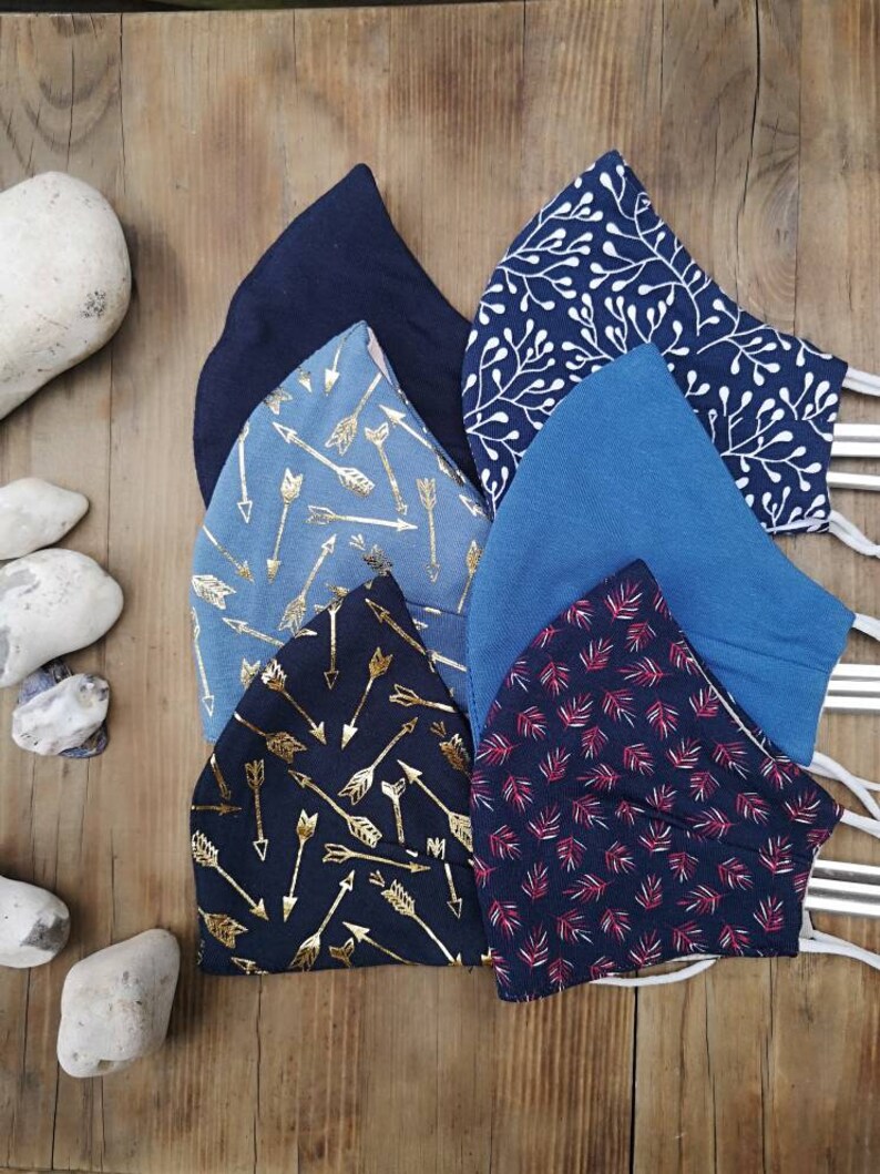May include: Six different fabric face masks with various patterns. The masks are blue, black, and red with white, gold, and silver accents. The patterns include arrows, leaves, and floral designs.