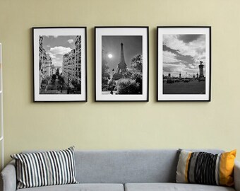 May include: Three black and white framed photographs of Paris, France. The first photo shows a street lined with buildings. The second photo shows the Eiffel Tower. The third photo shows a bridge with a view of the city.