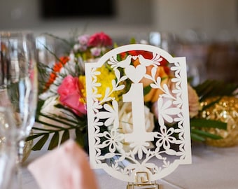 Witte tafelnummers in Papel Picado-stijl met metallic look en tortelduifjes.