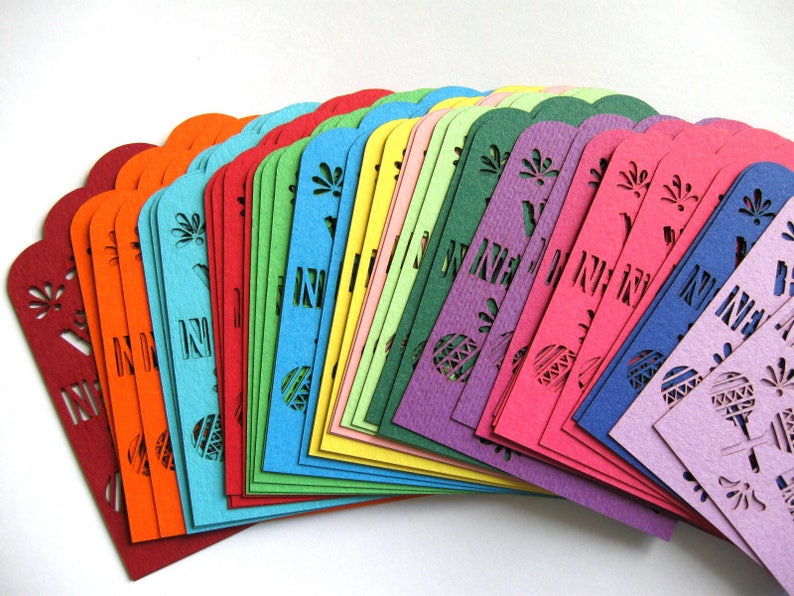 Puede incluir: Un abanico de recortes de papel de colores con dise&ntilde;os intrincados. Cada recorte es de un color diferente, que van del rojo al morado. Los recortes est&aacute;n dispuestos en forma de abanico, con el recorte m&aacute;s grande en la parte inferior y el m&aacute;s peque&ntilde;o en la parte superior.