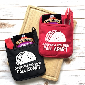 May include: Two black and red oven mitts with a white taco graphic and the text "Every now and then fall apart".