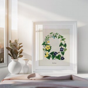 May include: A white framed print of a botanical illustration of a wreath of yellow and purple flowers with green leaves. The text "The Wreath" is printed below the wreath.