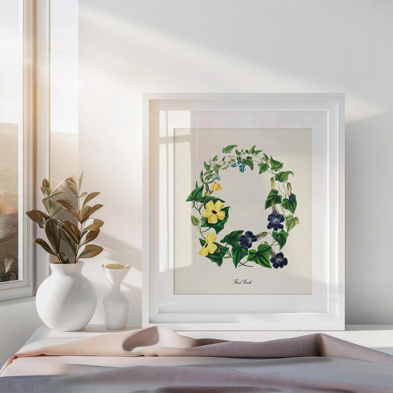May include: A white framed print of a botanical illustration of a wreath of yellow and purple flowers with green leaves. The text "The Wreath" is printed below the wreath.