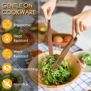 May include: Two wooden kitchen utensils, a spatula and a fork, are being used to toss a salad in a wooden bowl. The utensils are labeled "Gentle on Cookware" and have icons indicating they are ergonomic, heat resistant, wear resistant, non-scratching, and non-stick.
