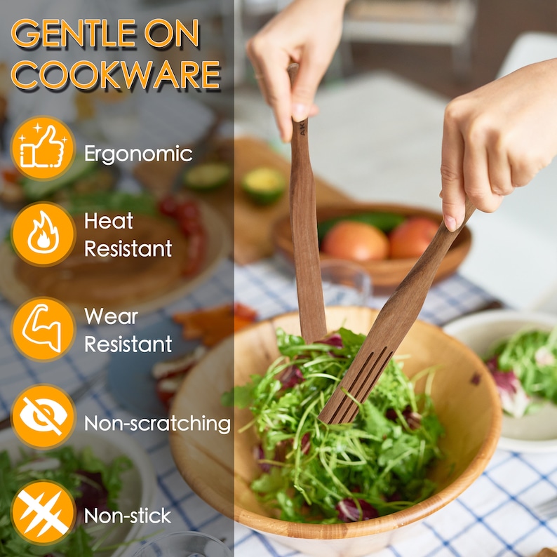 May include: Two wooden kitchen utensils, a spatula and a fork, are being used to toss a salad in a wooden bowl. The utensils are labeled "Gentle on Cookware" and have icons indicating they are ergonomic, heat resistant, wear resistant, non-scratching, and non-stick.